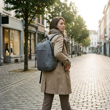Stijlvolle vrouw met anti-diefstal rugzak loopt door een Europese straat, met hand op verborgen rits en een verfijnde, praktische reislook.